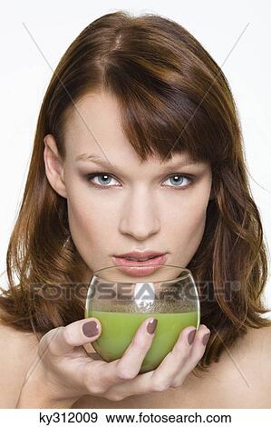 Young woman holding glass of wheatgrass juice View Large Photo Image Stock Photo - Young woman holding glass of wheatgrass juice. Fotosearch