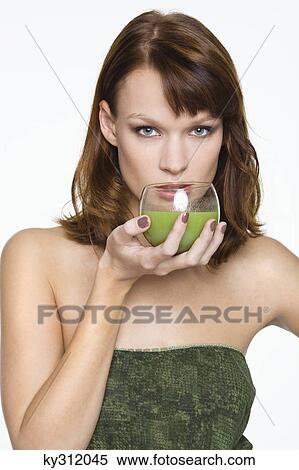 Young woman holding glass of wheatgrass juice View Large Photo Image Stock Photography - Young woman holding glass of wheatgrass juice. Fotosearch