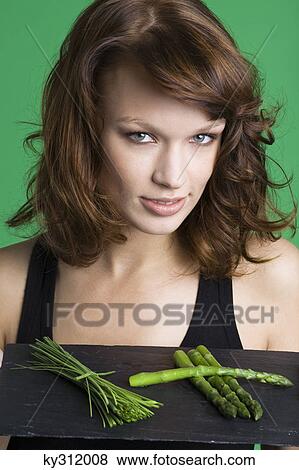 Young woman holding tray of asparagus and chives View Large Photo Image Stock Photo - Young woman holding tray of asparagus and chives. Fotosearch
