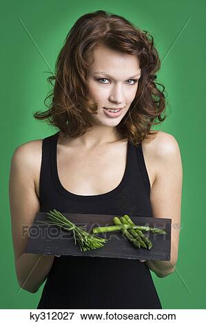 Young woman holding tray of asparagus and chives View Large Photo Image Stock Photo - Young woman holding tray of asparagus and chives. Fotosearch