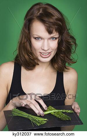Young woman holding tray of asparagus and chives View Large Photo Image Stock Photo - Young woman holding tray of asparagus and chives. Fotosearch