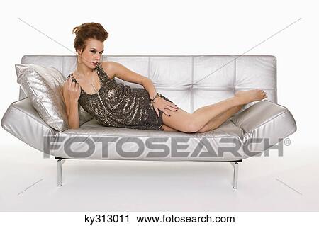 Stock Image - Young woman in formalwear lying on sofa. Fotosearch