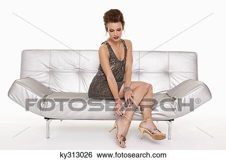 Stock Photograph - Young woman in formalwear putting on shoe. Fotosearch