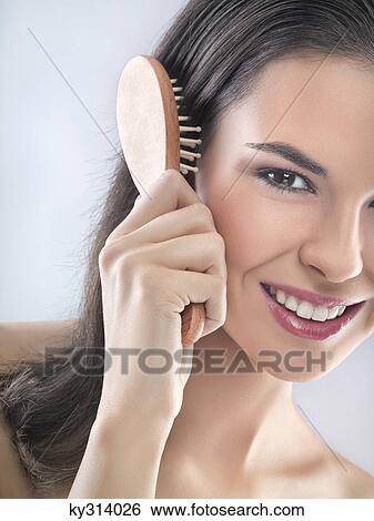 Young woman brushing her hair View Large Photo Image Stock Photograph - Young woman brushing her hair. Fotosearch