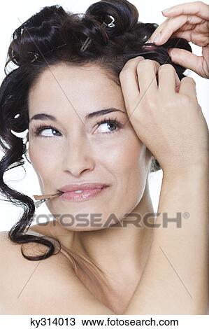 Stock Image - Young woman fixing hair clips. Fotosearch