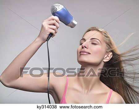 Young woman using hair dryer View Large Photo Image Stock Photo - Young woman using hair dryer. Fotosearch