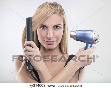 Young woman using hair straighteners and hair dryer View Large Photo Image Stock Image - Young woman using hair straighteners and hair dryer. Fotosearch