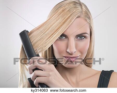Young woman using hair straighteners View Large Photo Image Stock Image - Young woman using hair straighteners. Fotosearch
