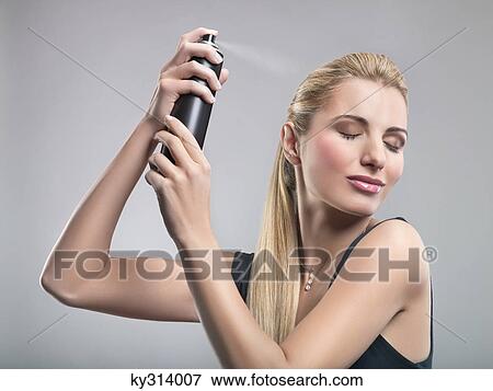Young woman using hairspray View Large Photo Image Stock Photo - Young woman using hairspray. Fotosearch