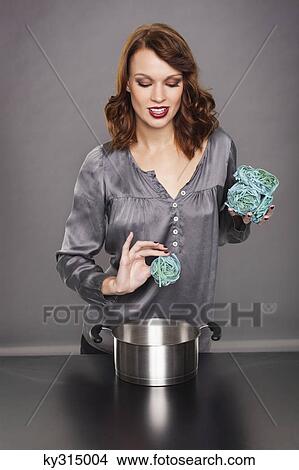 Picture - Young woman cooking seaweed pasta. Fotosearch