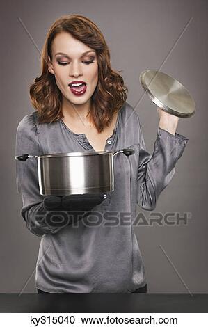 Young woman looking at content of stew pot View Large Photo Image Stock Image - Young woman looking at content of stew pot. Fotosearch