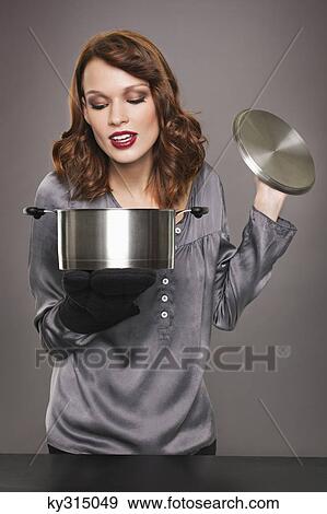 Young woman looking at content of stew pot View Large Photo Image Stock Photo - Young woman looking at content of stew pot. Fotosearch