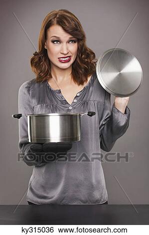 Young woman looking at content of stew pot View Large Photo Image Stock Photograph - Young woman looking at content of stew pot. Fotosearch