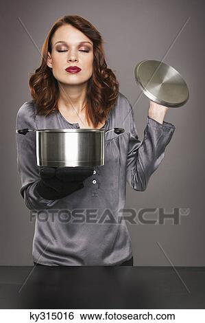 Young woman smelling aroma from stew pot View Large Photo Image Stock Photograph - Young woman smelling aroma from stew pot. Fotosearch