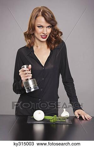 Stock Image - Young woman using onion chopper. Fotosearch