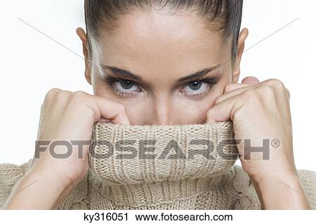 Stock Image - Young woman covering her face with sweater. Fotosearch