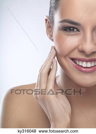 Stock Photo - Young woman rubbing her cheek. Fotosearch