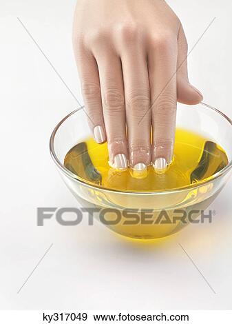 Stock Photo - Close-up of woman's hand in bowl of olive oil. Fotosearch