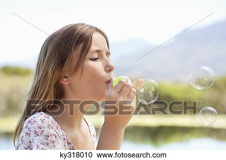Stock Image - Close-up of a girl blowing bubbles. Fotosearch