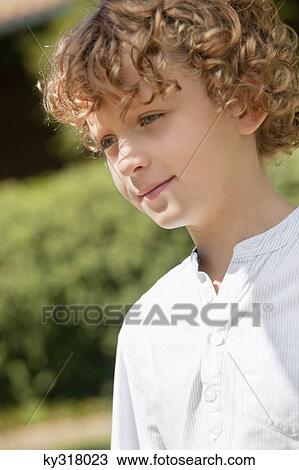 Stock Image - Close-up of smiling boy day dreaming. Fotosearch