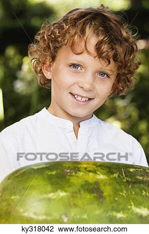 Close-up of smiling boy holding watermelon View Large Photo Image Stock Image - Close-up of smiling boy holding watermelon. Fotosearch