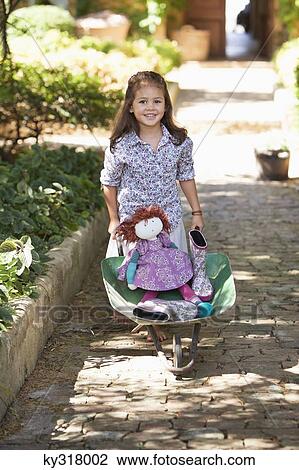 Cute girl pushing a wheelbarrow filled with toys View Large Photo Image Stock Image - Cute girl pushing a wheelbarrow filled with toys. Fotosearch