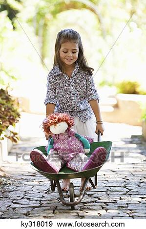 Stock Photo - Cute girl pushing a wheelbarrow filled with toys. Fotosearch