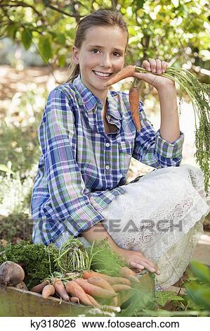 Girl crouching near a crate of vegetables View Large Photo Image Stock Photograph - Girl crouching near a crate of vegetables. Fotosearch