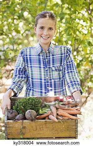 Girl holding a crate of vegetables View Large Photo Image Picture - Girl holding a crate of vegetables. Fotosearch