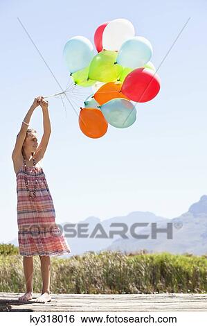 Girl playing with balloons at a pier View Large Photo Image Stock Photograph - Girl playing with balloons at a pier. Fotosearch