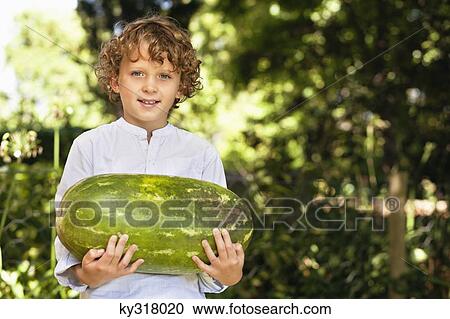 Stock Image - Portrait of a smiling boy holding a watermelon. Fotosearch