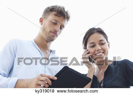 Low angle view of a young couple using electronic gadgets View Large Photo Image Stock Photo - Low angle view of a young couple using electronic gadgets. Fotosearch