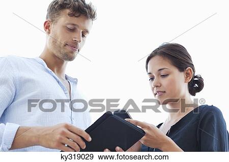 Low angle view of a young couple using electronic gadgets View Large Photo Image Stock Photo - Low angle view of a young couple using electronic gadgets. Fotosearch