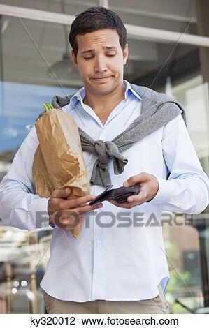 Mid adult man checking the empty wallet with paper bag full of vegetables View Large Photo Image Stock Image - Mid adult man checking the empty wallet with paper bag full of vegetables. Fotosearch