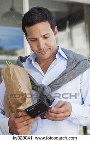Mid adult man checking the empty wallet with paper bag full of vegetables View Large Photo Image Stock Image - Mid adult man checking the empty wallet with paper bag full of vegetables. Fotosearch