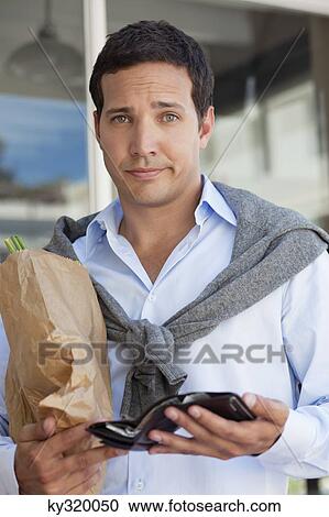 Portrait of a man showing empty wallet with paper bag full of vegetables View Large Photo Image Stock Image - Portrait of a man showing empty wallet with paper bag full of vegetables. Fotosearch
