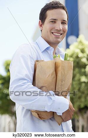 Portrait of a mid adult man holding paper bags full of vegetables and smiling View Large Photo Image Stock Image - Portrait of a mid adult man holding paper bags full of vegetables and smiling. Fotosearch