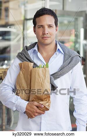 Portrait of a mid adult man holding paper bags full of vegetables View Large Photo Image Stock Photo - Portrait of a mid adult man holding paper bags full of vegetables. Fotosearch