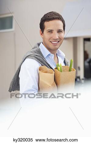 Portrait of a mid adult man holding paper bags full of vegetables and smiling View Large Photo Image Stock Photography - Portrait of a mid adult man holding paper bags full of vegetables and smiling. Fotosearch