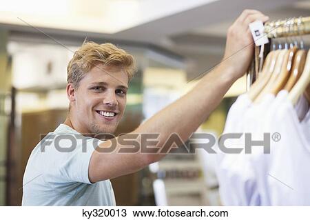 Portrait of a young man standing in a clothing store View Large Photo Image Stock Image - Portrait of a young man standing in a clothing store. Fotosearch
