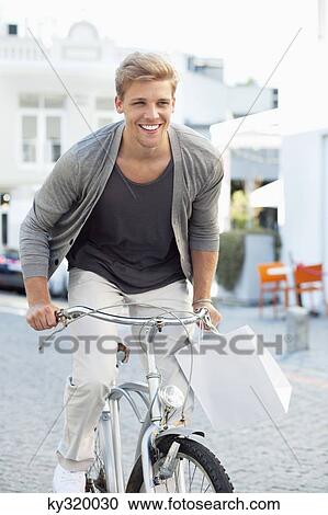 Smiling young man cycling View Large Photo Image Stock Image - Smiling young man cycling. Fotosearch