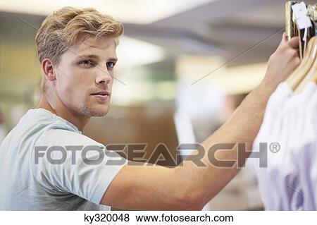Young man standing in a clothing store View Large Photo Image Stock Photo - Young man standing in a clothing store. Fotosearch