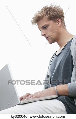 Young man using a laptop View Large Photo Image Stock Photograph - Young man using a laptop. Fotosearch
