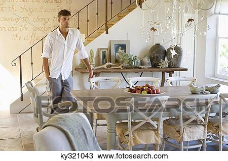 Man standing by the dining table with hand in pocket View Large Photo Image Stock Image - Man standing by the dining table with hand in pocket. Fotosearch
