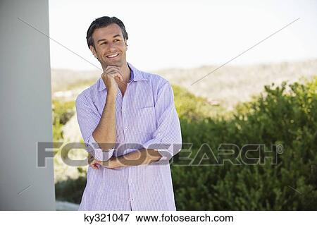 Man standing with his hand on his chin and smiling View Large Photo Image Stock Photo - Man standing with his hand on his chin and smiling. Fotosearch