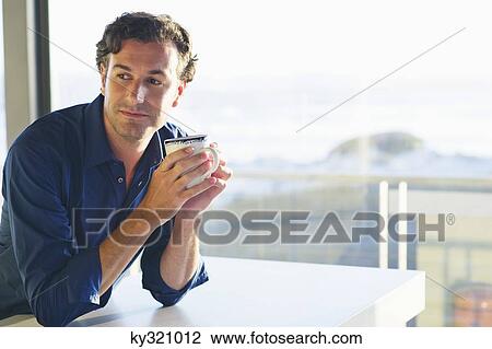 Mid adult man drinking coffee View Large Photo Image Stock Image - Mid adult man drinking coffee. Fotosearch