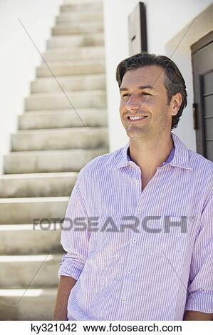 Mid adult man leaning against a wall View Large Photo Image Stock Image - Mid adult man leaning against a wall. Fotosearch