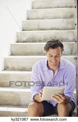 Mid adult man using a digital tablet View Large Photo Image Stock Photo - Mid adult man using a digital tablet. Fotosearch