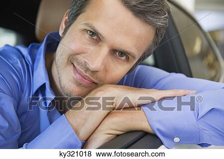 Portrait of a happy mid adult man leaning on car window View Large Photo Image Stock Photo - Portrait of a happy mid adult man leaning on car window. Fotosearch