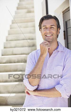 Stock Image - Portrait of a mid adult man leaning against a wall. Fotosearch